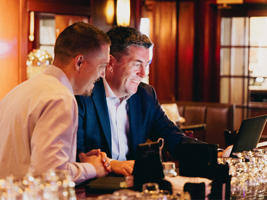 Justin with resturant owner client looking at a laptop screen